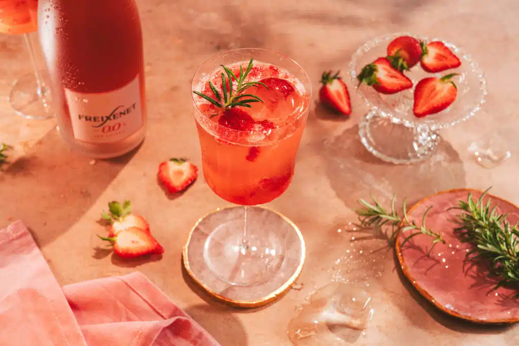 Rosé-Drinks mit Erdbeeren und Rosmarin auf einem Holztisch