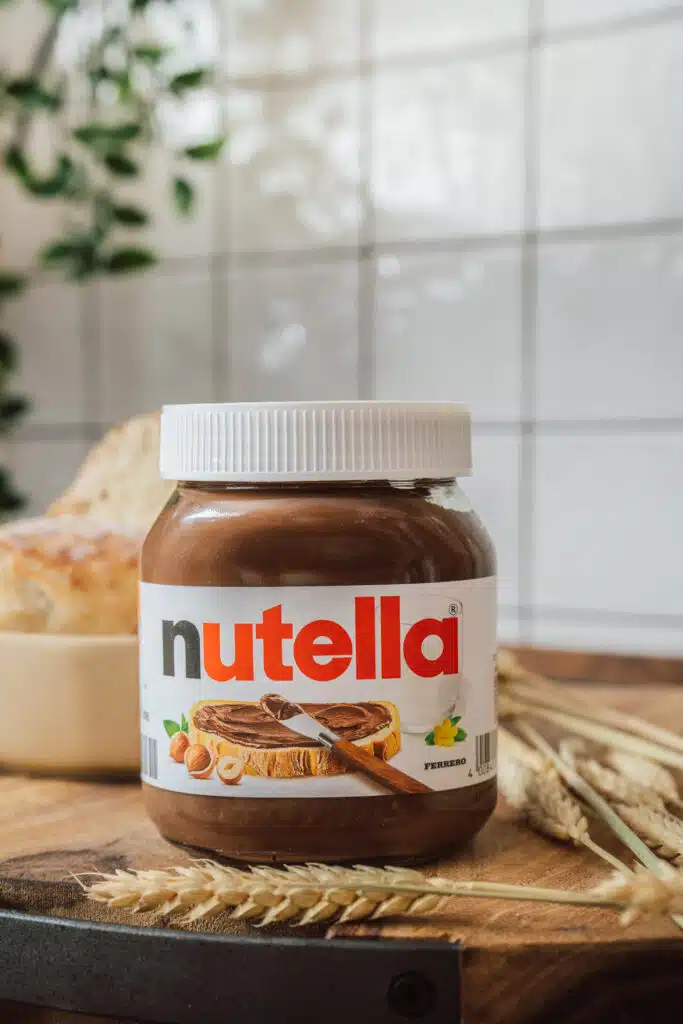 Nutella-Glas vor gefliester Wand mit Brötchen