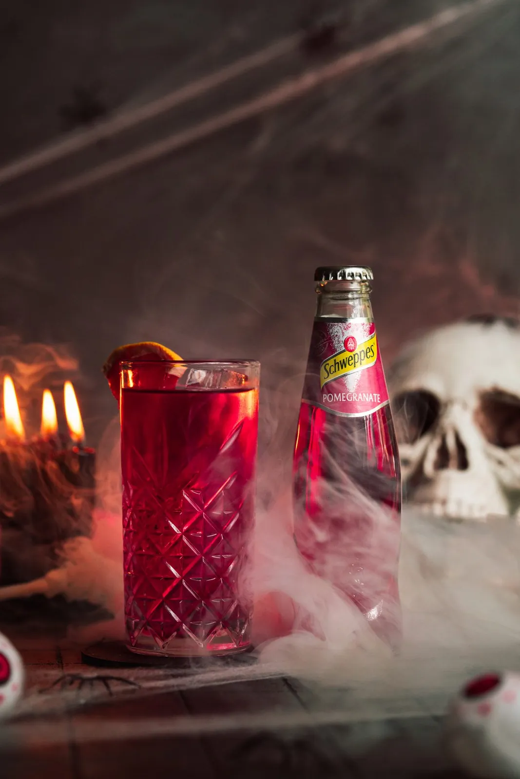 Roter Halloween-Drink mit Schweppes, Kerzen und Nebel