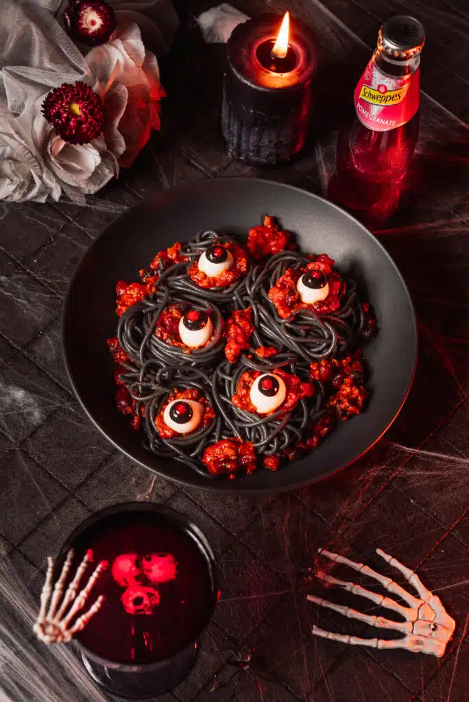 Halloween-Tafel mit schwarzer Pasta und Augen-Deko