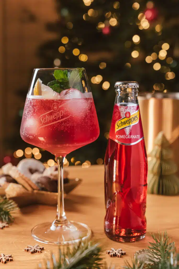 Roter Drink vor einem Weihnachtsbaum mit Schweppes-Flasche