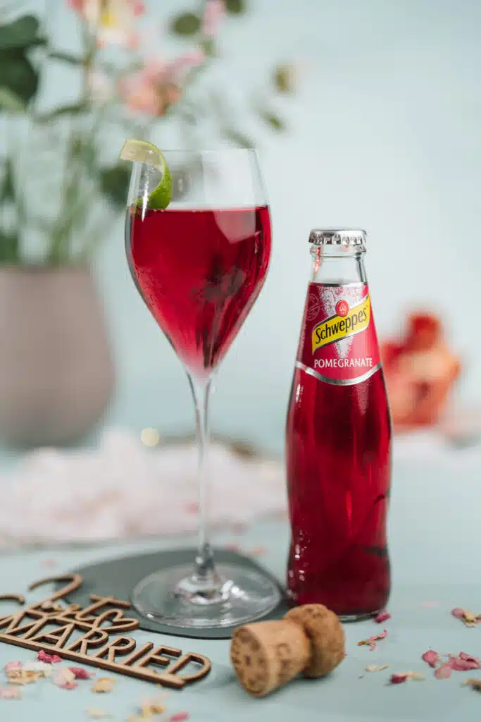 Granatapfel-Spritz im Weinglas mit Schweppes-Flasche