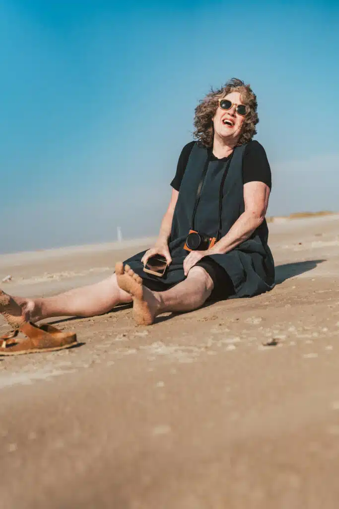 Frau sitzt lachend am Strand von Fanø