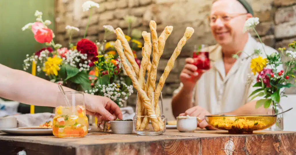 Tafel mit Grissini im Glas und Gästen im Garten